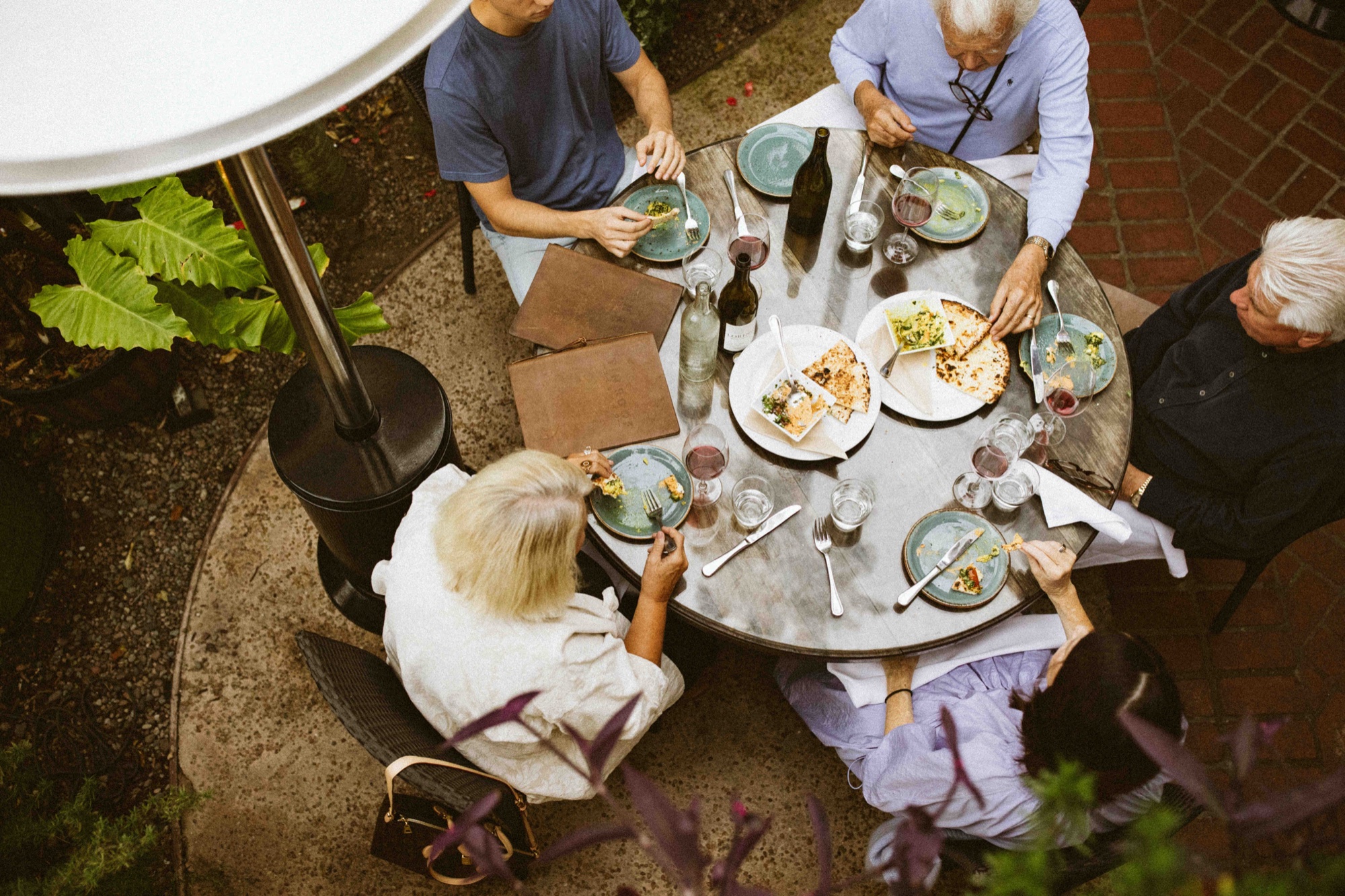 Guests sharing wood-fired pizza on the courtyard patio at Tin Roof Bistro